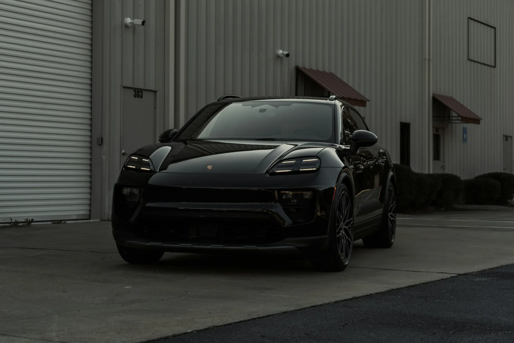 Schwarzer Porsche Macan von vorne vor einer Halle